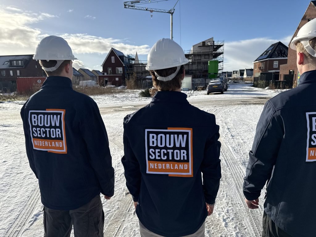 Schilders van Bouwsector Nederland met witte bouwhelm bekijken nieuwe woningen in aanbouw in de winter